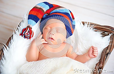 Cute newborn baby in blue knit cap sleeping in basket Stock Photo