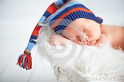 Cute newborn baby in blue knit cap sleeping in basket Stock Photo