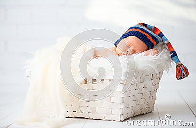 Cute newborn baby in blue knit cap sleeping in basket Stock Photo