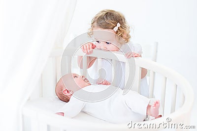 Cute newborn baby boy watching his toddler sister standing at hi Stock Photo