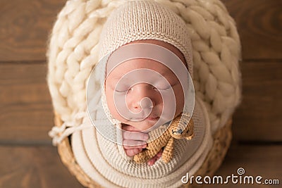 Cute newborn baby in a knitted hat in a wooden basket and with a little bear toy Stock Photo