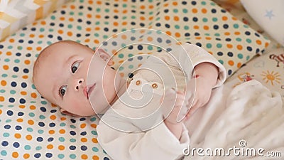 Cute newborn baby is lying in the crib. Beautiful baby lies in the crib at home Cute newborn baby is lying in the crib. Beautiful baby lies in the crib at home