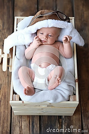 Cute newborn baby wearing aviator hat in crate, top view Stock Photo