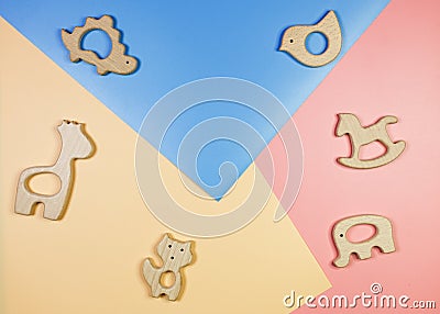 Cute nice small wooden baby teethers with different shapes on blue yellow pink background. Eco accessories for newborn. Stock Photo