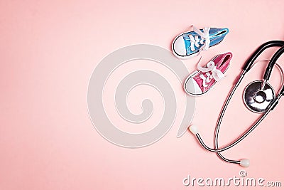 Cute pink baby girl and blue baby boy shoes with stethoscope on pink background. Top view with copy space Stock Photo