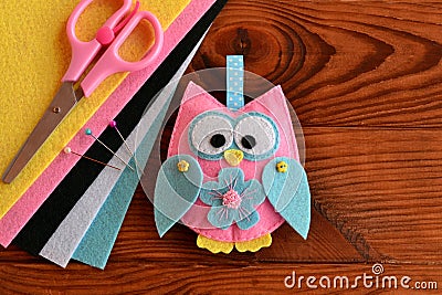Cute pink and blue owl toy, colored felt sheets, scissors on a wooden table. Fabric owl embellishment Stock Photo