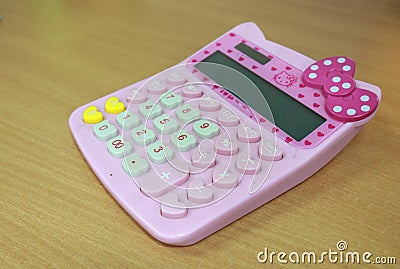 A cute pink calculator for calculating tools for children and adults is on the table Stock Photo