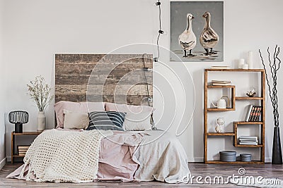 Cute poster with two ducks on white wall of tasteful bedroom interior with bed with pastel pink bedding Stock Photo