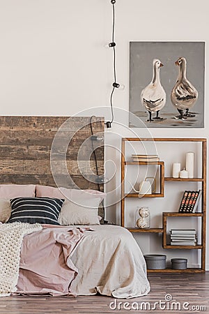 Cute poster with two ducks on white wall of tasteful bedroom interior with bed with pastel pink bedding Stock Photo