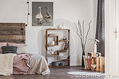 Cute poster with two ducks on white wall of tasteful bedroom interior with bed with pastel pink bedding Stock Photo