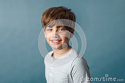 A cute pre-teen tween boy from the shoulders up on a muted blue backdrop Stock Photo