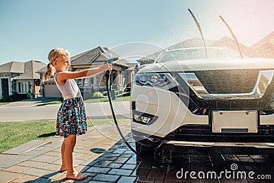 Girl washing car on driveway in front house on sunny summer day Stock Photo