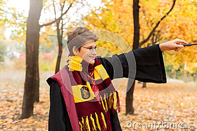 Cute pretty boy in costume of Harry Potter and scarf plays as a magician, reads book in autumn Editorial Stock Photo
