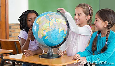 Cute pupils sitting in classroom with globe Stock Photo