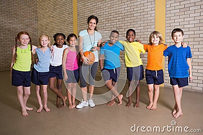 Cute pupils smiling at camera with PE teacher Stock Photo