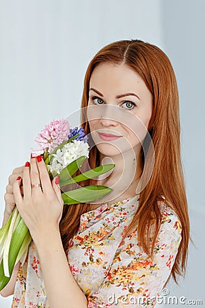 Cute red-haired girl holding flowers and smiling, close-up Stock Photo