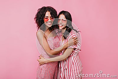 Cute romantic girls hug each other in friendly way. Ladies in pink sunglasses laughing on isolated Stock Photo