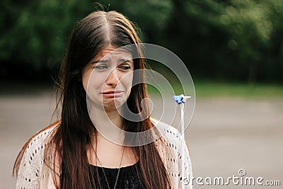 cute sad woman looking at banged blue balloon with crying emotion Stock Photo
