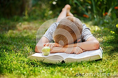 Cute school boy lying on a green grass who does not want to read the book. boy sleeping near books Stock Photo