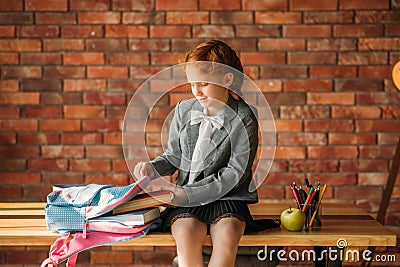 Cute schoolgirl puts textbook into the schoolbag Stock Photo