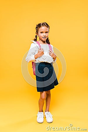 cute schoolkid touching pink backpack while standing on orange . Stock Photo