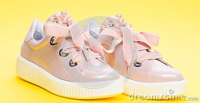 Cute shoes on yellow background. Footwear for girls or women decorated with pearl beads. Pair of pale pink female Stock Photo