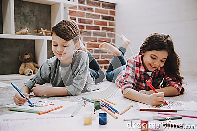 Cute Siblings Drawing Pictures Laying at Floor Stock Photo