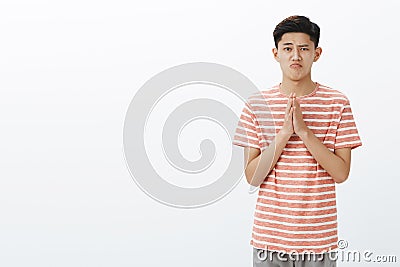 Cute silly guy sincerely asking forgiveness or permission, holding hands in pray over chest making cute gloomy Stock Photo