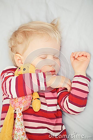 Cute sleeping blond baby with toy Stock Photo