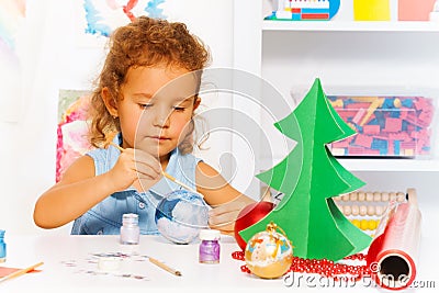 Cute small girl paints New Year ball for Xmas tree Stock Photo