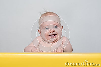 Cute smiling baby looking at the camera. Toddler sits at the table Stock Photo