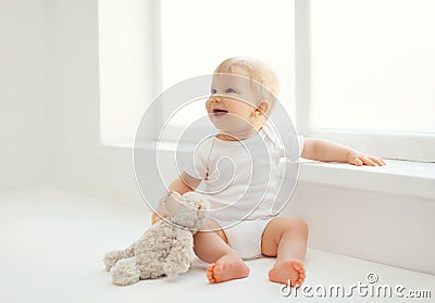 Cute smiling baby with teddy bear toy sitting at home Stock Photo