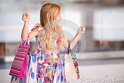 Cute smiling child girl 4-5 year old hold paper bags shopping in store mall making purchases. Buy clothes with season sales. Stock Photo