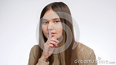 Cute smiling girl holding finger at mouth in shhh gesture after telling secret Stock Photo