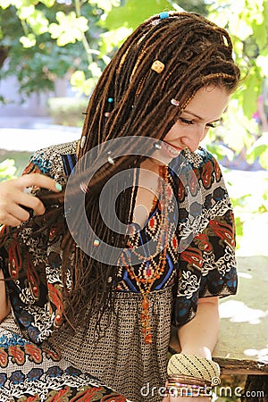 Cute smiling hippie indie style woman with dreadlocks, dressed in boho style ornamental dress posing Stock Photo