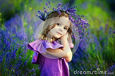Cute smiling little girl with flower wreath on the meadow at the farm. Portrait of adorable small kid outdoors Stock Photo