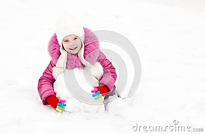 Cute smiling little girl makes snowman in winter day Stock Photo