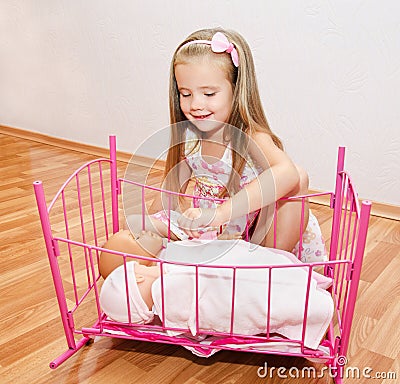Cute smiling little girl playing with her newborn baby dolls Stock Photo