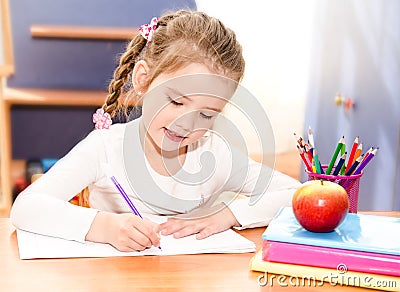 Cute smiling little girl is writing at the desk Stock Photo