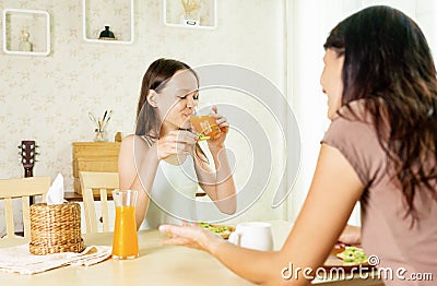 Cute smiling preteen girl having healthy breakfast with mom: avocado sandwich and orange juice. Healthy lifestyle concept, vegetar Stock Photo