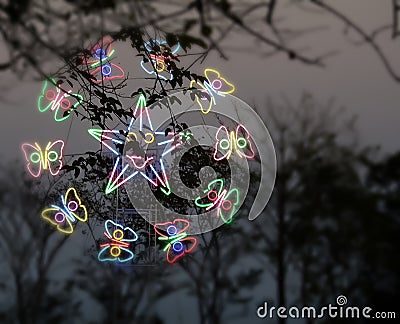 Cute smiling star and butterfly ferris wheel over trees in fun fair Stock Photo