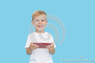 Cute smilling child boy with smartphone on blue background. Advertising of educational applications on a mobile Stock Photo