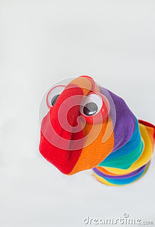 Cute sock puppet with rainbow flag sock, and plastic red eyes. White background, copy space. Fighting for LGBTQ+ rights Stock Photo
