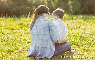 Cute son giving a bouquet of flowers to his mother sitting in a Stock Photo