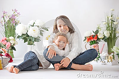 Cute stylish toddler child and older brother, boys with white shirt, playing with eggs and chocolate bunny on Easter decoration Stock Photo