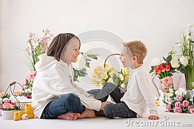 Cute stylish toddler child and older brother, boys with white shirt, playing with eggs and chocolate bunny on Easter decoration Stock Photo