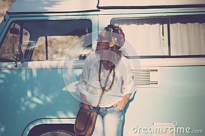 Cute stylish trendy adult caucasian woman stand up with blue vintage van in background - concept of travel and fashion driver Stock Photo