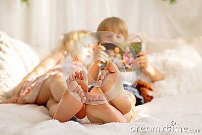 Cute sweet toddler children, tickling feet on the bed, laughing and smiling Stock Photo