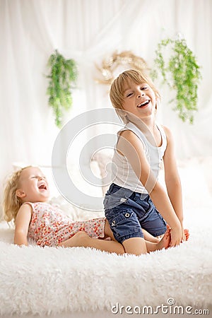 Cute sweet toddler children, tickling feet on the bed, laughing and smiling Stock Photo