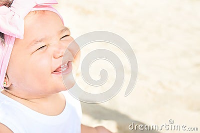 Cute Sweet 1 Year Old Baby Girl Toddler Sits on Beach Sand by Ocean Smiling. Sweet Face Expression. Bright Sunny Day. Parenting Stock Photo